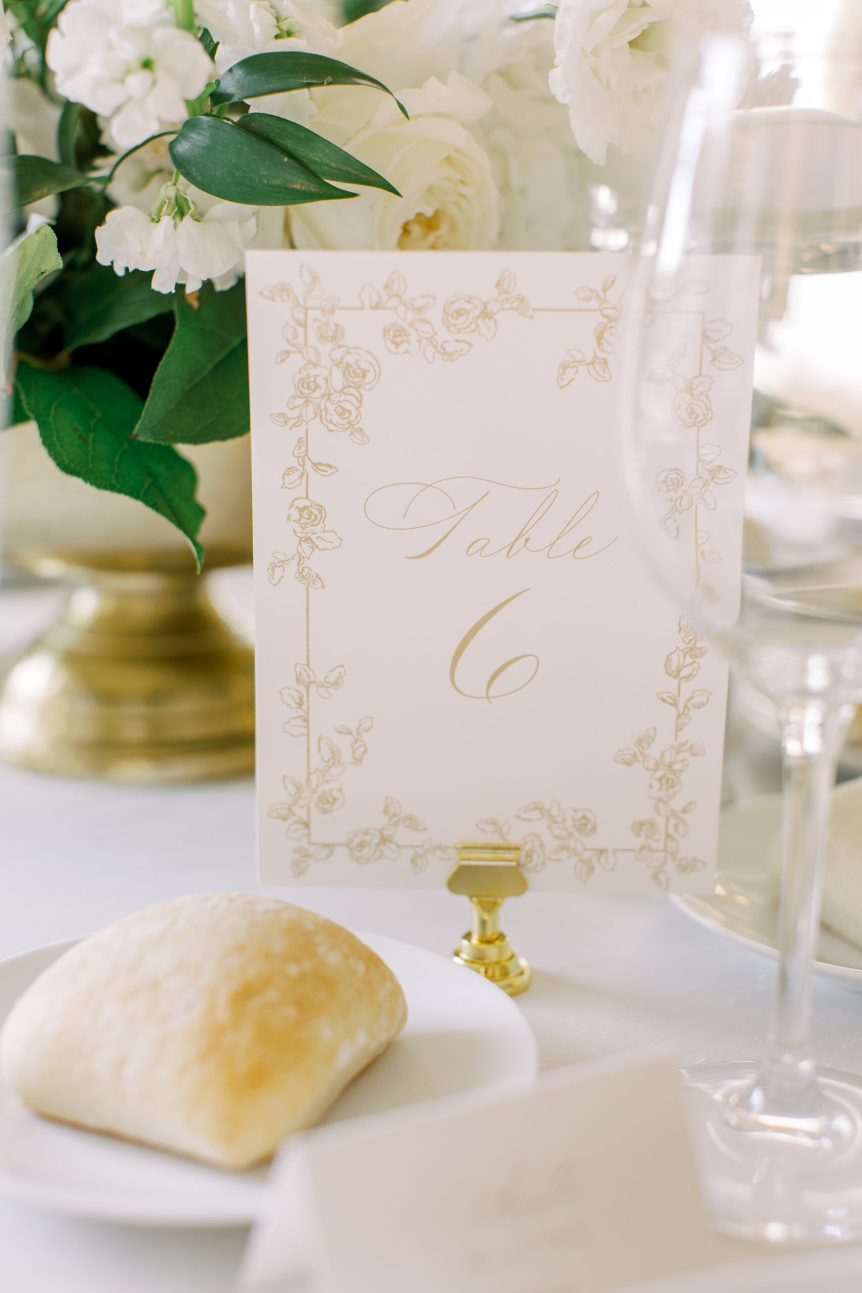 Elegant table number card with gold floral detailing and ‘Table 6’ script, part of the reception design thoughtfully curated in the couple’s wedding weekend itinerary