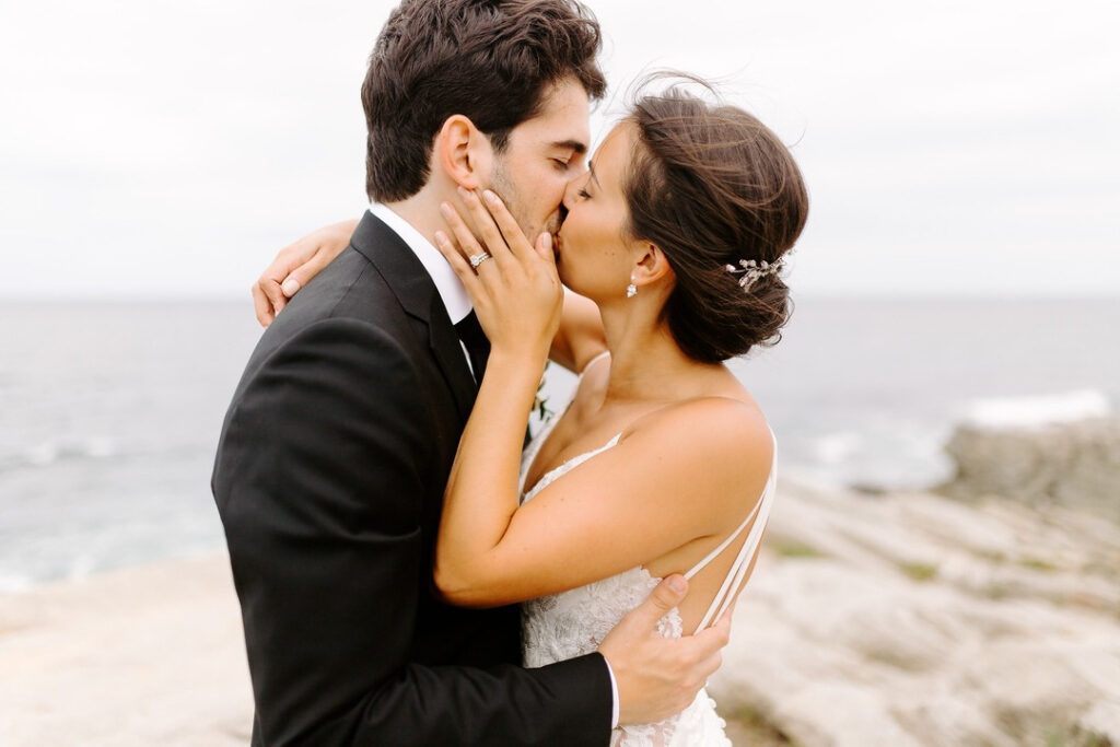wedding couple kissing with ocean in the background