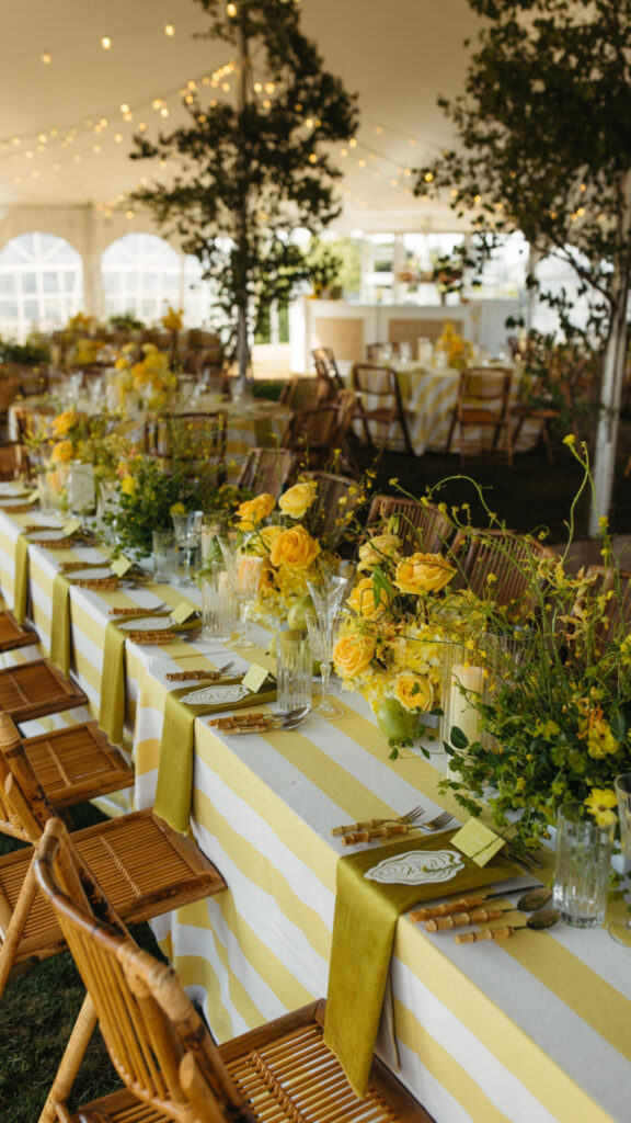 Striped yellow reception tablescape with fresh florals at a full-service wedding weekend in New England.
