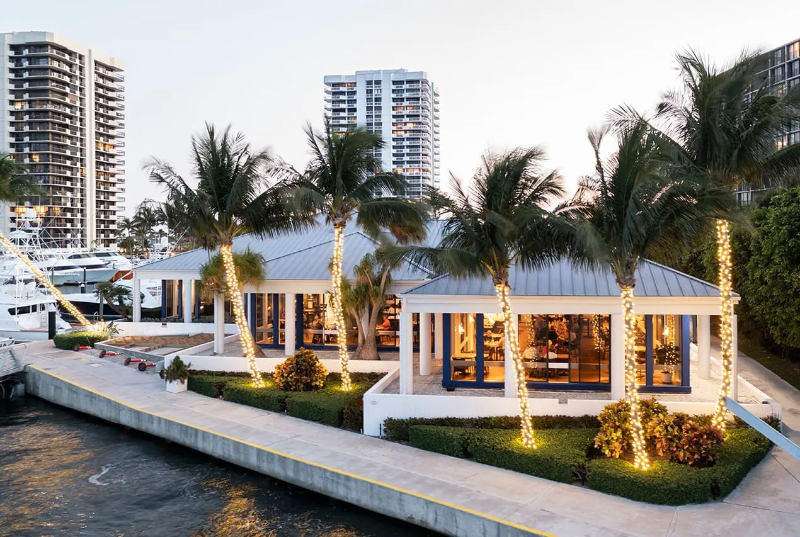 Waterfront venue with palm trees and glowing lights, perfect for a luxurious full-service wedding weekend celebration