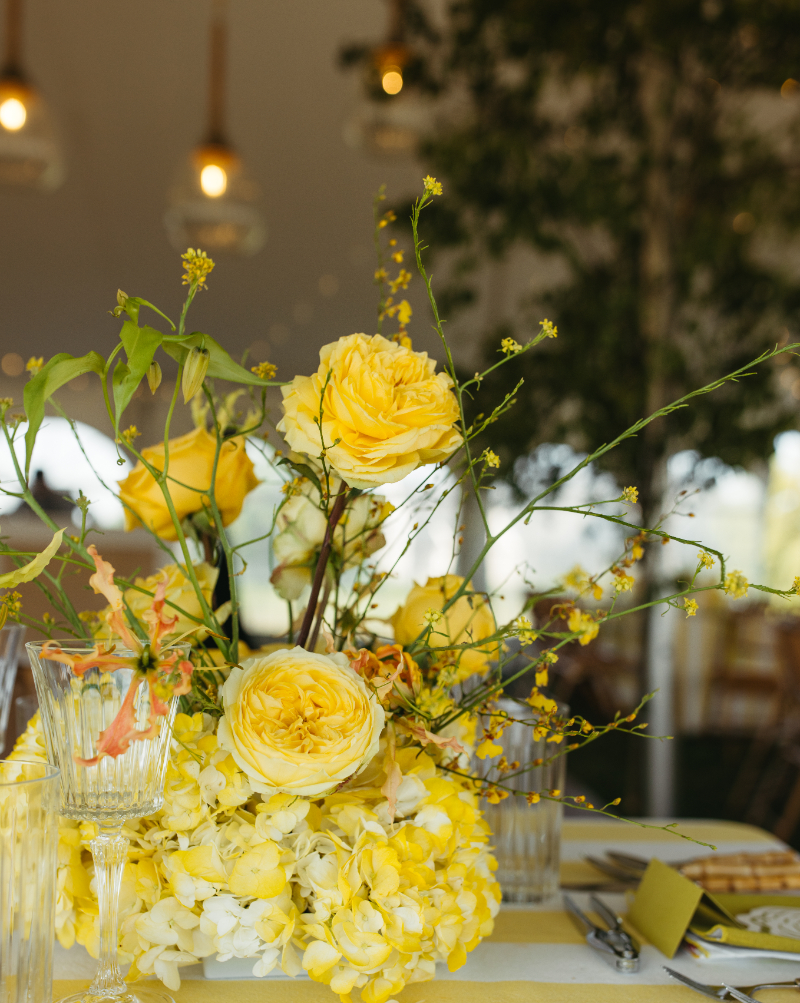 Yellow floral centerpiece with textured blooms and natural branches styled for 2026 wedding design trends.