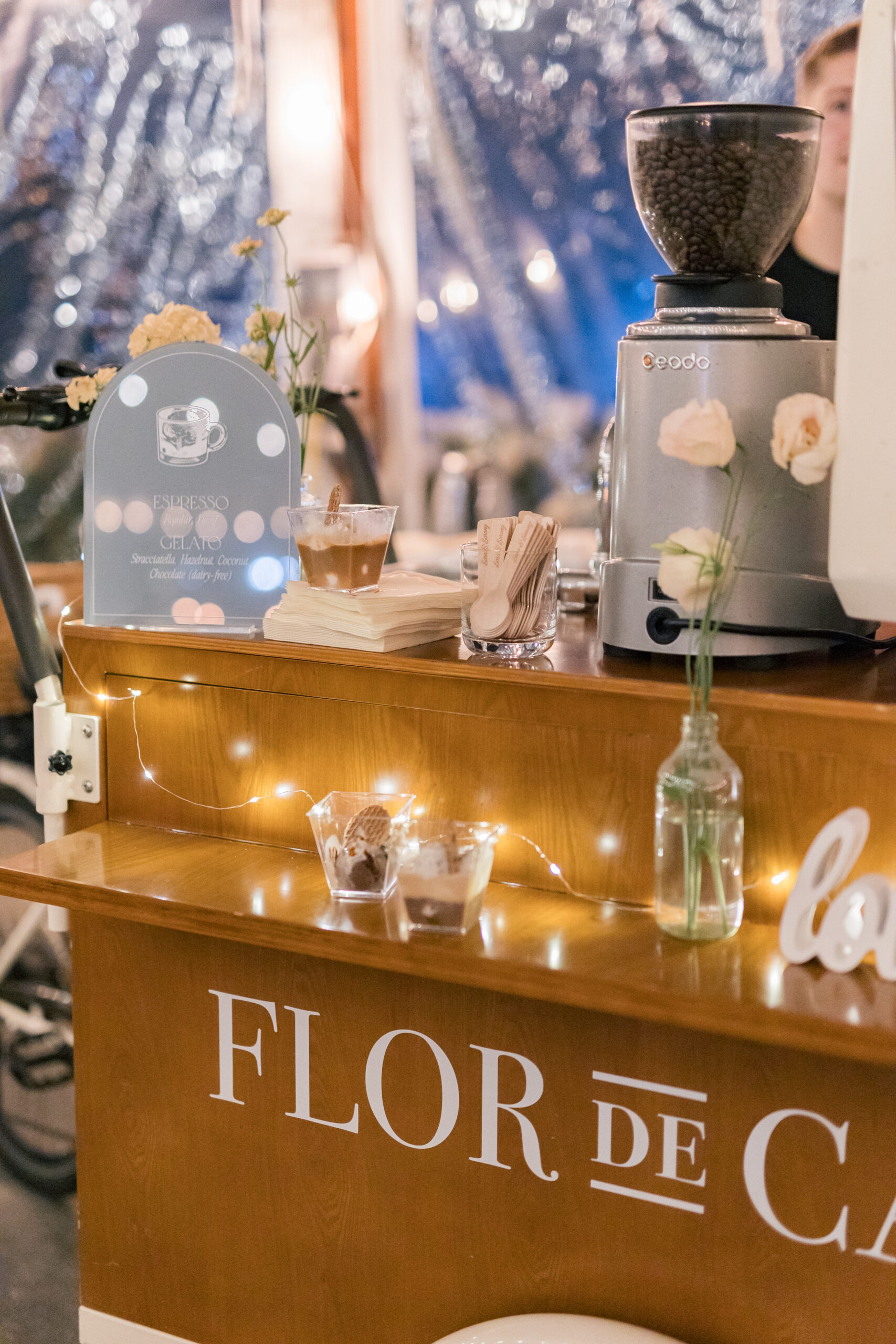Cozy coffee bar with flowers, warm lights, and espresso setup showcasing 2026 Wedding Design Trends ambiance.