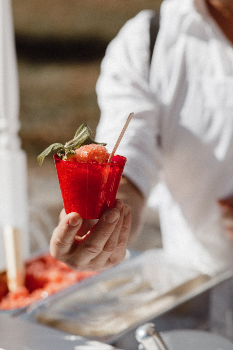 Hand holding a red cup of strawberry granita, a fun way to infuse Italian culinary culture.