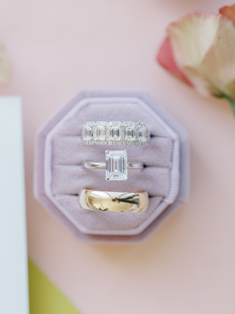 Wedding rings displayed in velvet box with diamond engagement ring.