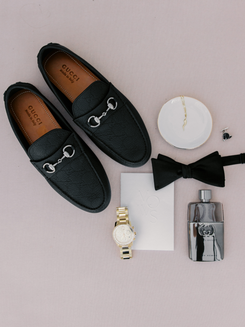 Groom details including black loafers, bow tie, watch, and cologne.