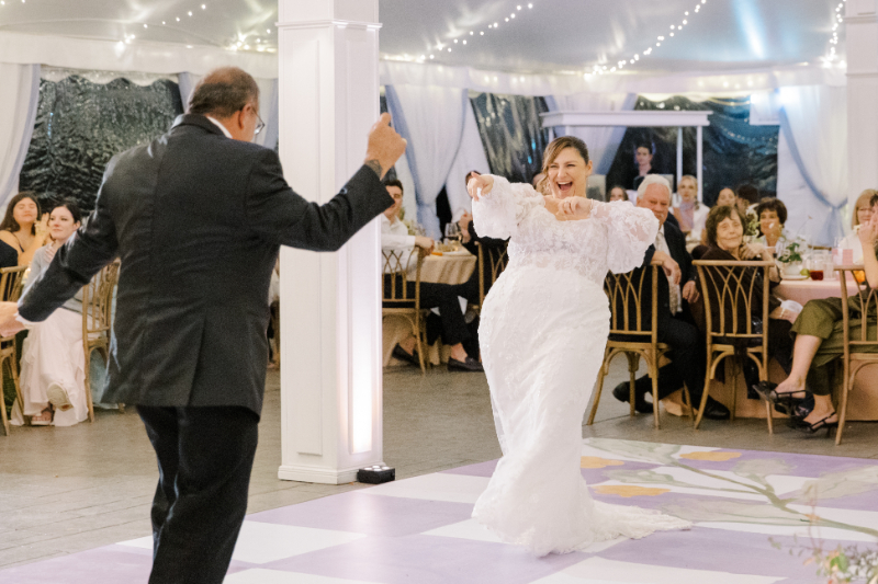 Bride and father dancing joyfully during reception inside tent at a Blithewold Mansion wedding