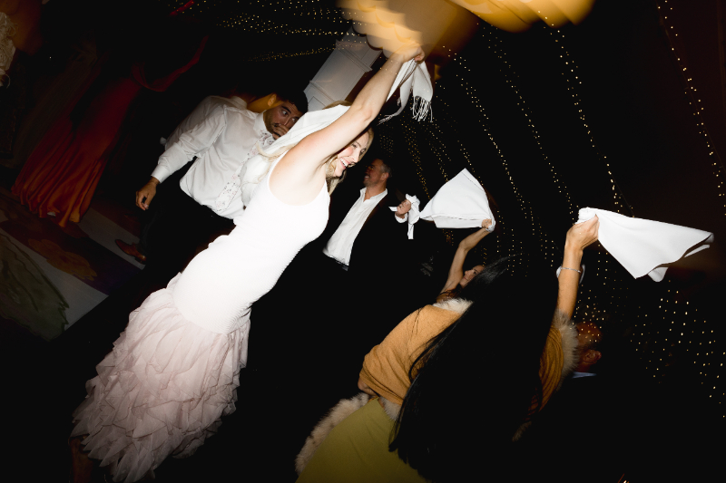 Bride waving napkin while dancing with guests at evening reception at Blithewold Mansion wedding