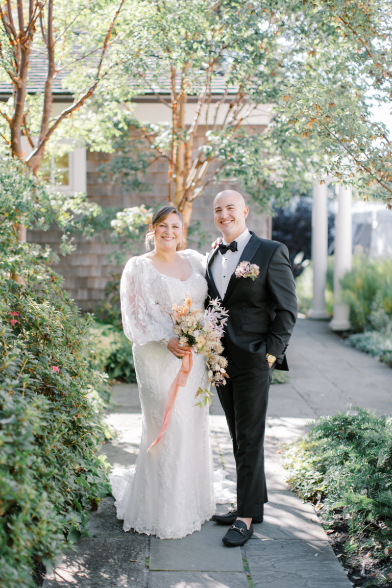 Bride and groom standing together in garden walkway after ceremony.