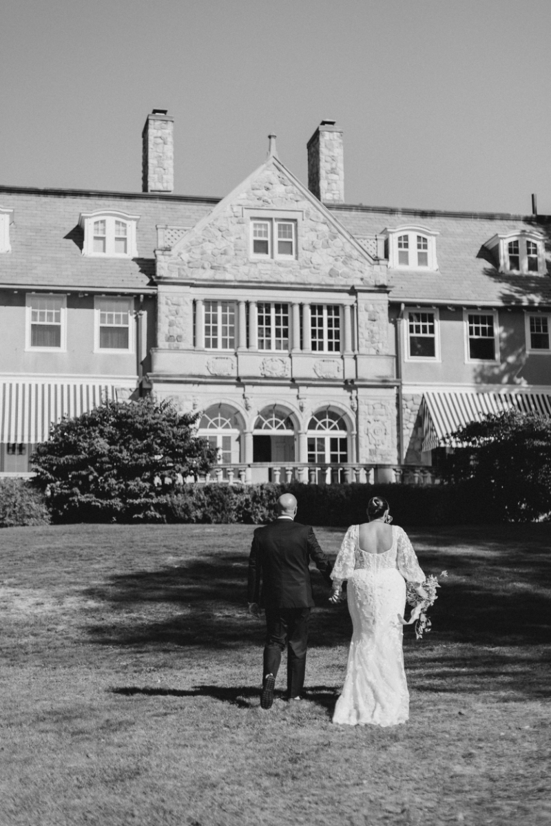 Bride and groom walking across lawn toward Blithewold Mansion wedding