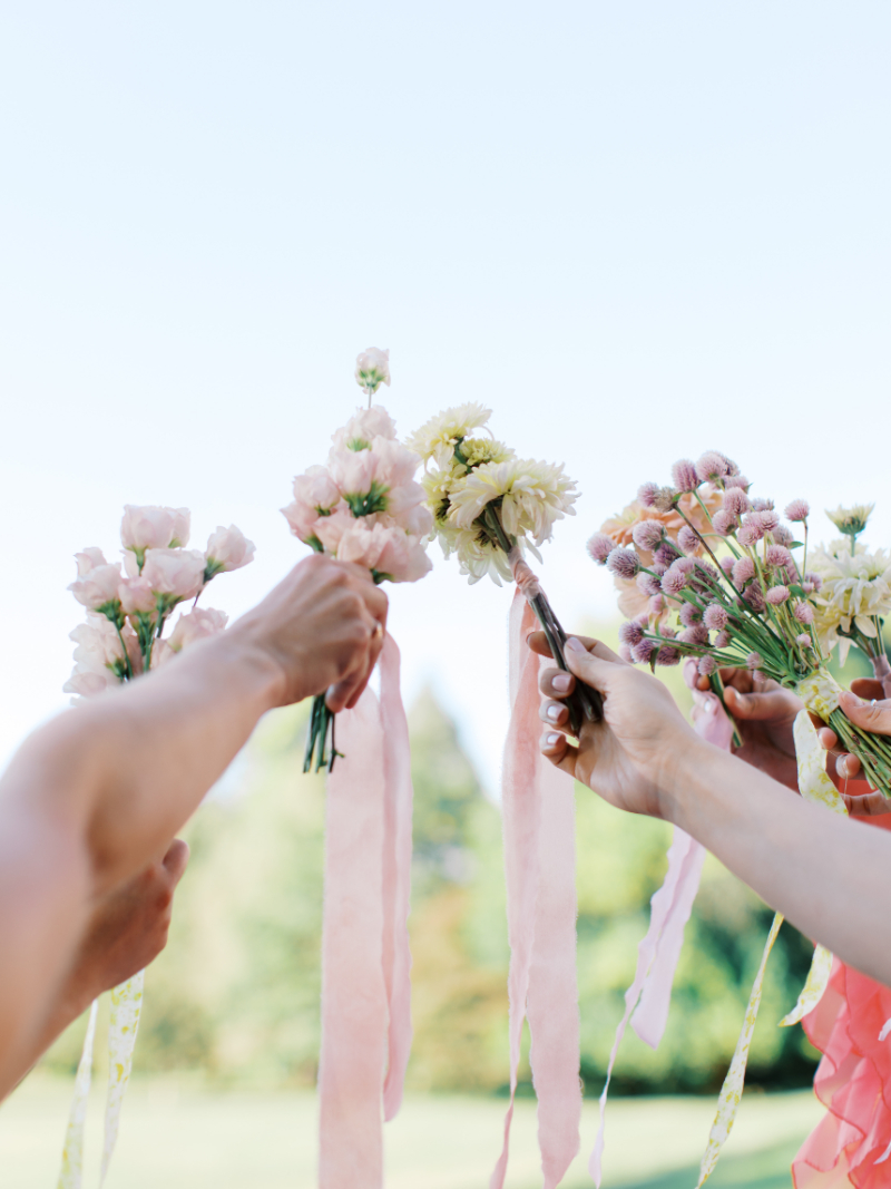 Bridesmaids holding pastel bouquets with flowing pink and green ribbons.