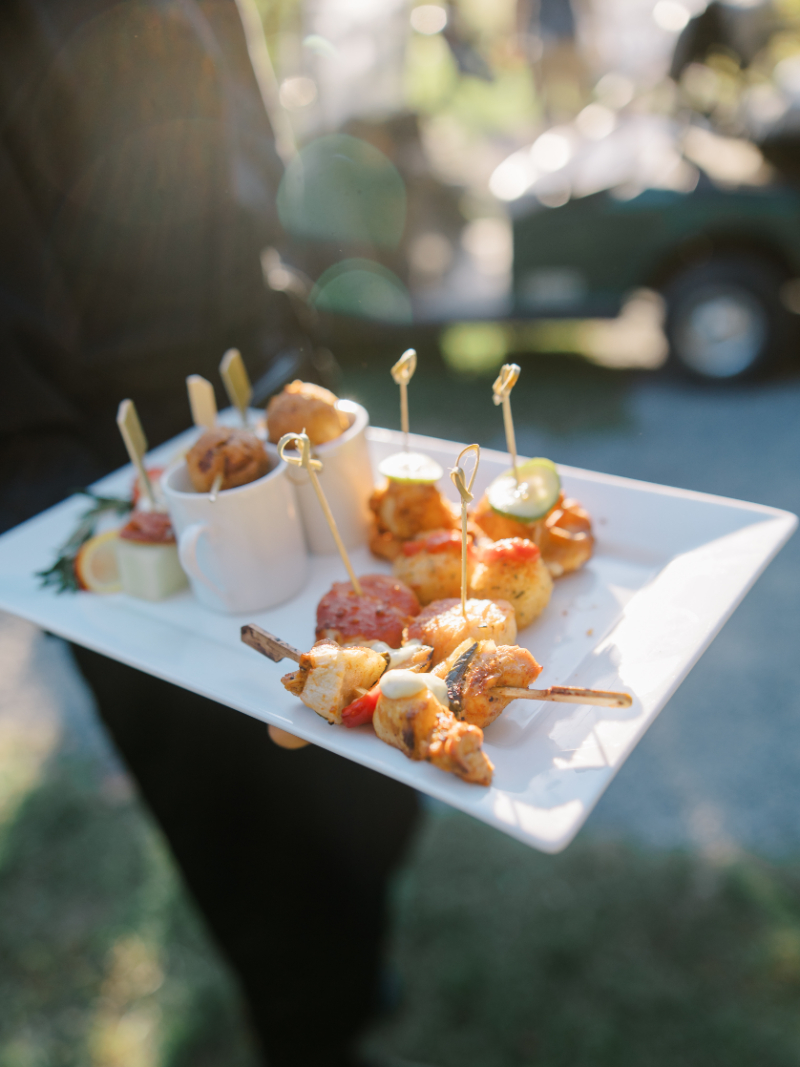 Assorted cocktail hour appetizers served on white tray in evening light.