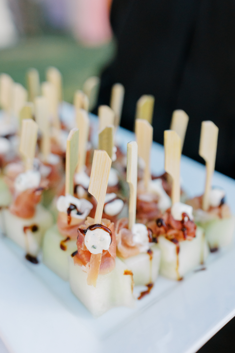 Passed caprese skewers with balsamic drizzle and wooden picks on platter.