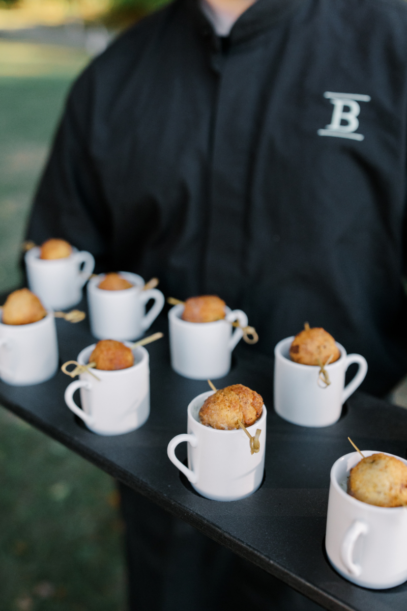Mini savory bites served in small espresso cups on black tray.