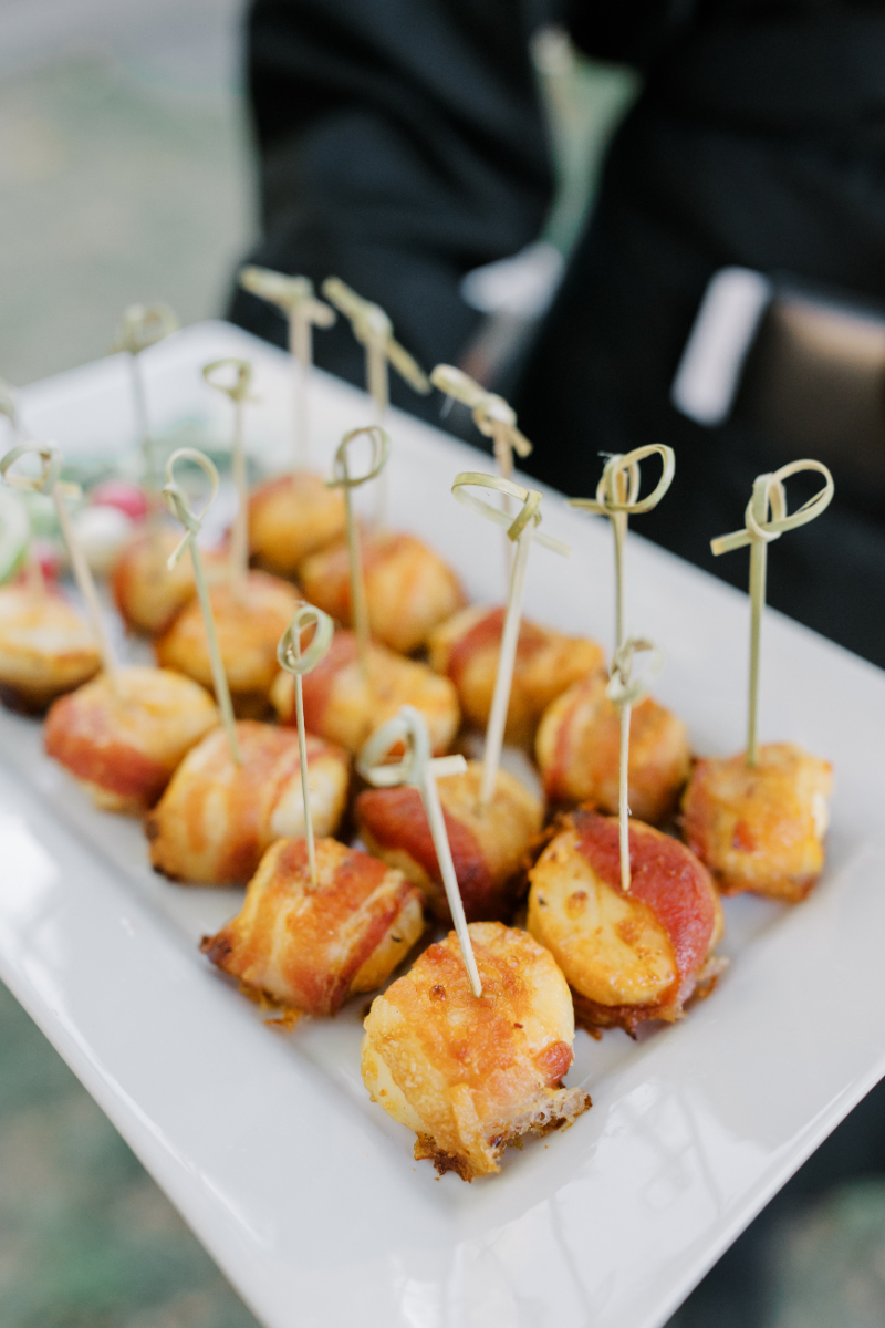 Bite sized appetizers with toothpicks presented on white serving tray.