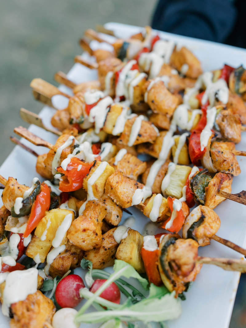 Passed chicken skewers with grilled vegetables and drizzle served on platter.