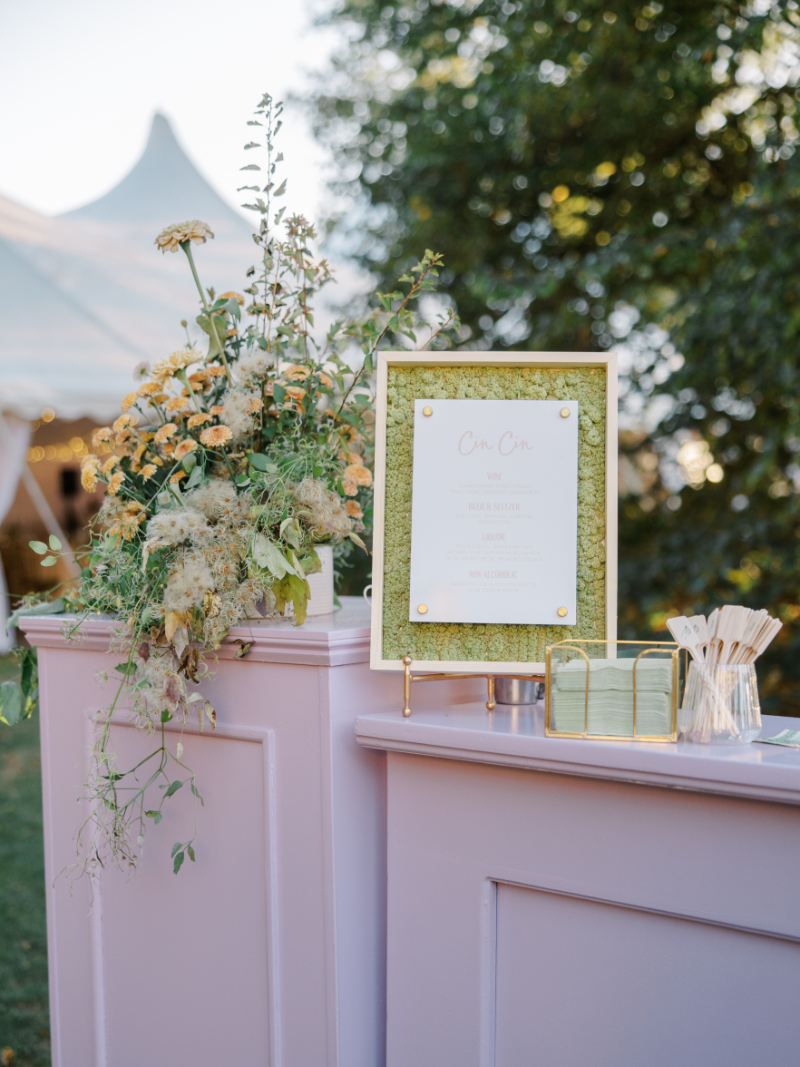 Blithewold Mansion wedding escort display with pastel bar, floral arrangements, and framed signage.