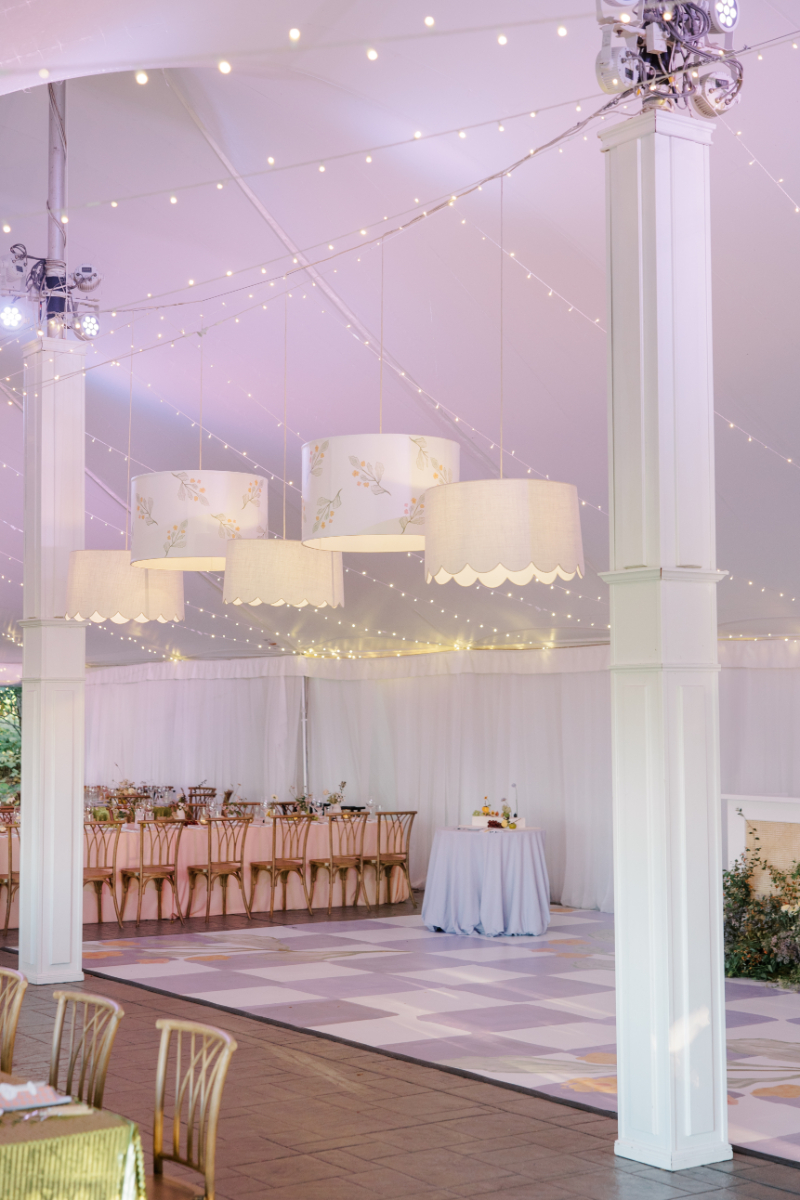 Reception tent interior with pastel dance floor and hanging drum shades.