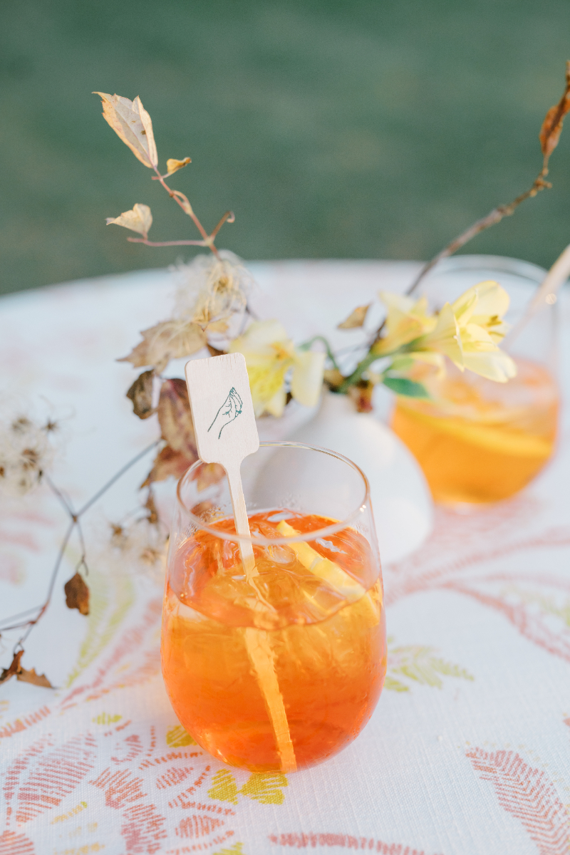 Aperol spritz cocktail with citrus garnish and custom stir stick.
