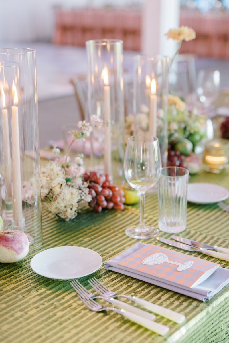 Candlelit tablescape with glass hurricanes, pastel florals, and layered place settings.