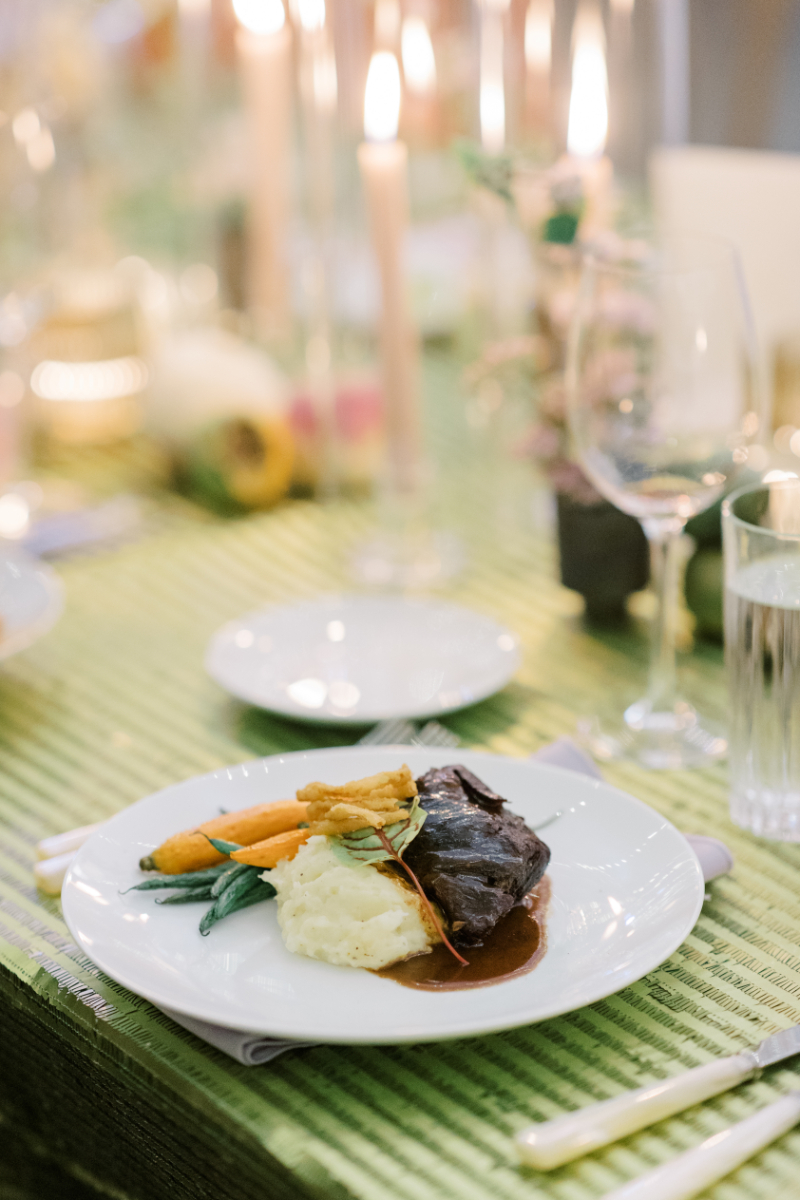 Plated steak dinner with mashed potatoes and vegetables on green linen table at a Blithewold Mansion wedding 