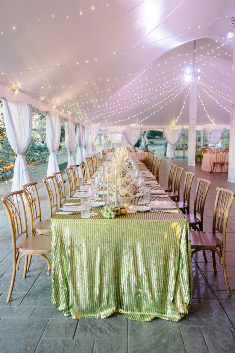 Blithewold Mansion wedding long table with green sequin linen and string lights overhead.
