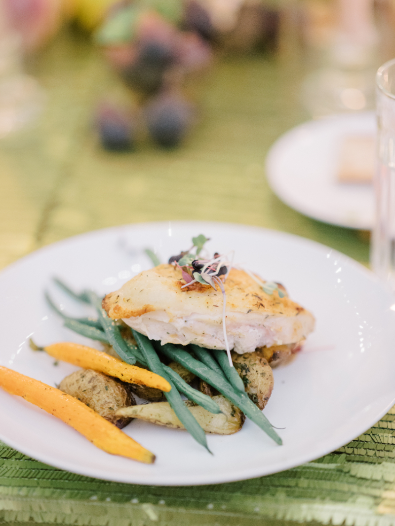 Plated dinner with roasted fish, green beans, and potatoes on textured linen.