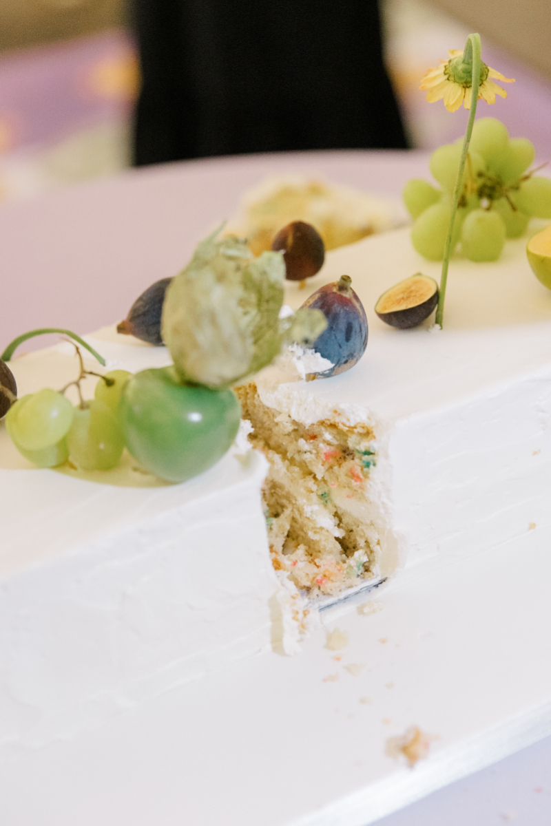 Rectangular wedding cake slice with fruit garnish and textured white icing.