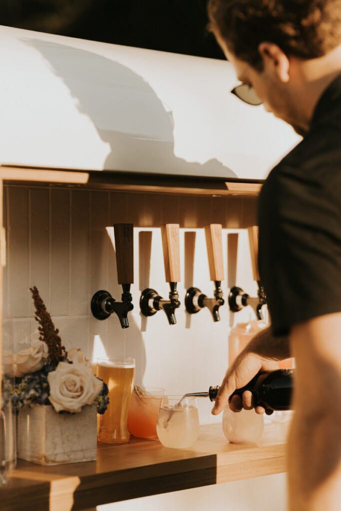 Bartender pouring drinks at Italian countryside wedding reception bar.