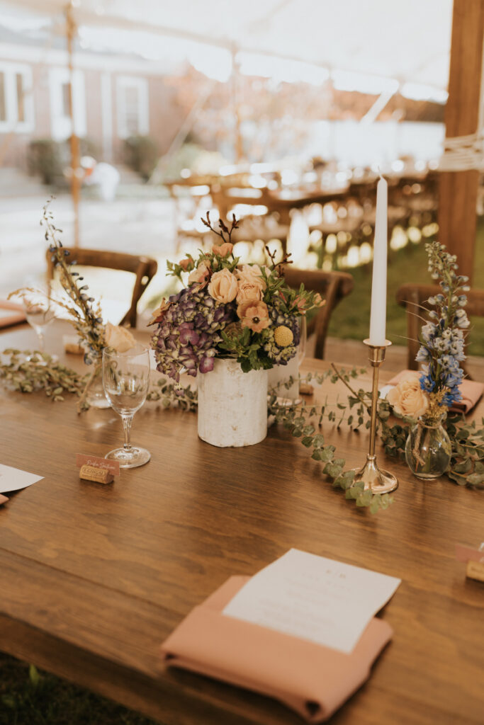Floral and candle detail on wooden table at Italian countryside wedding.