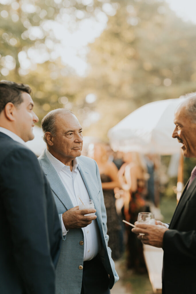 Guests mingling with drinks at Italian countryside wedding celebration.