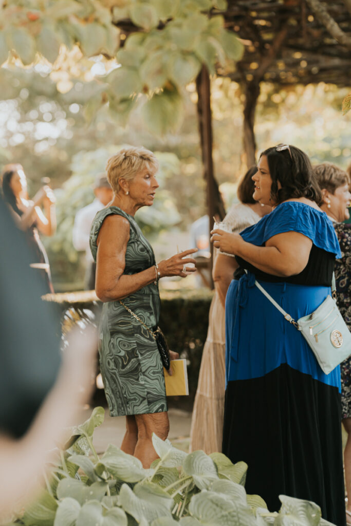 Guests chatting during Italian countryside wedding cocktail hour outdoors.
