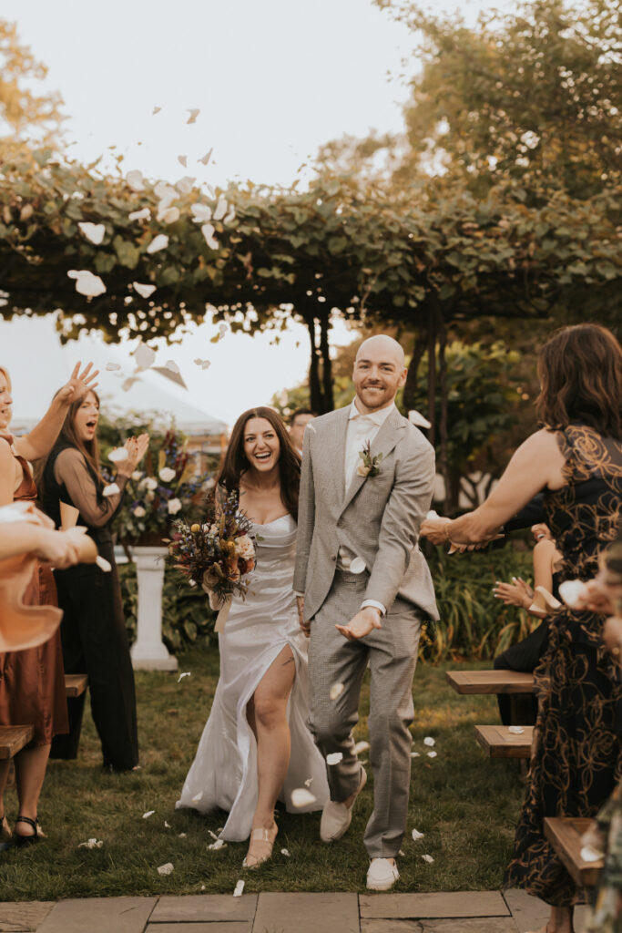 Bride and groom walking through guests during a wedding recessional.