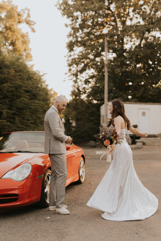 Bride twirling beside red convertible 