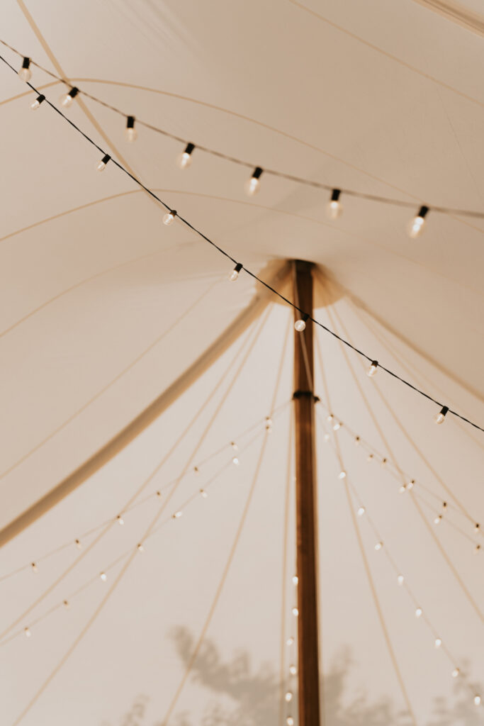 String lights inside reception tent at Italian countryside wedding dinner.