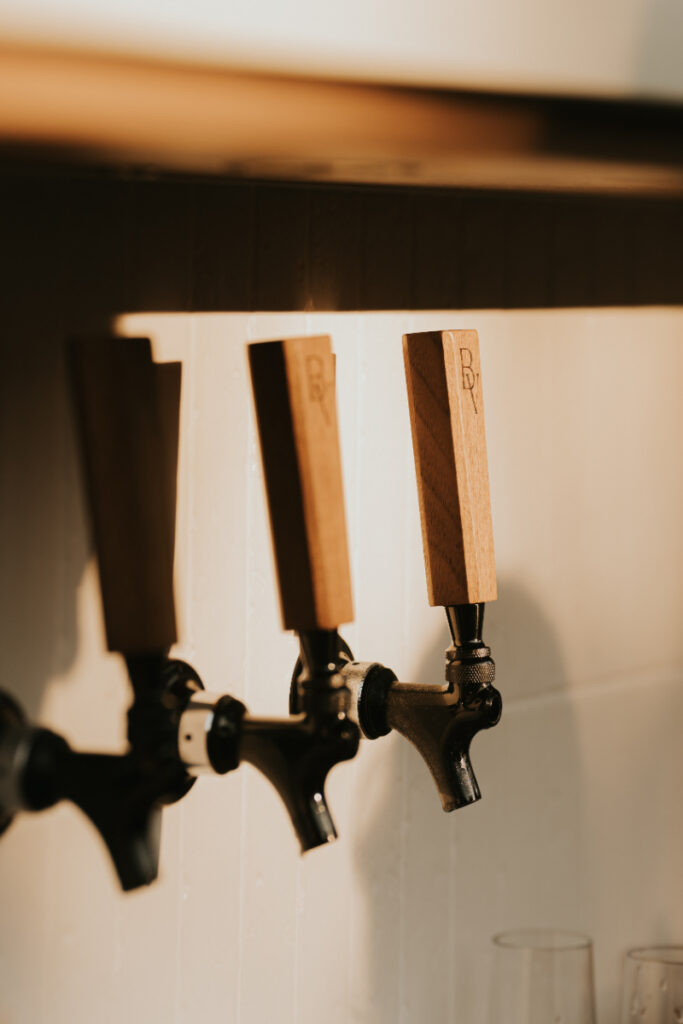 Cocktail taps and signature drinks at Italian countryside wedding reception bar.