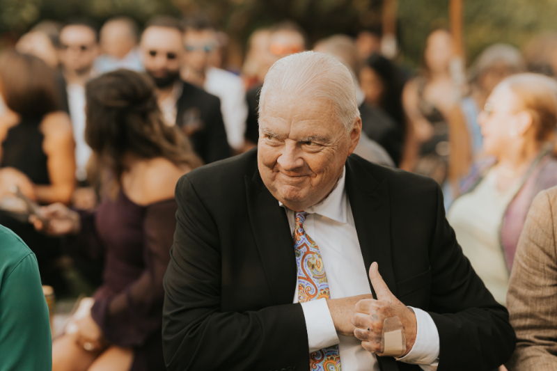 Guest smiling during Italian countryside wedding celebration outdoors.