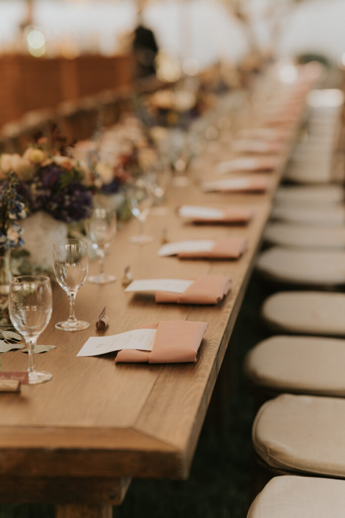 Long wooden dinner table setup at Italian countryside wedding reception.