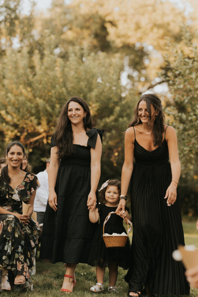 Bridesmaids and flower girl walking at Italian countryside wedding ceremony.
