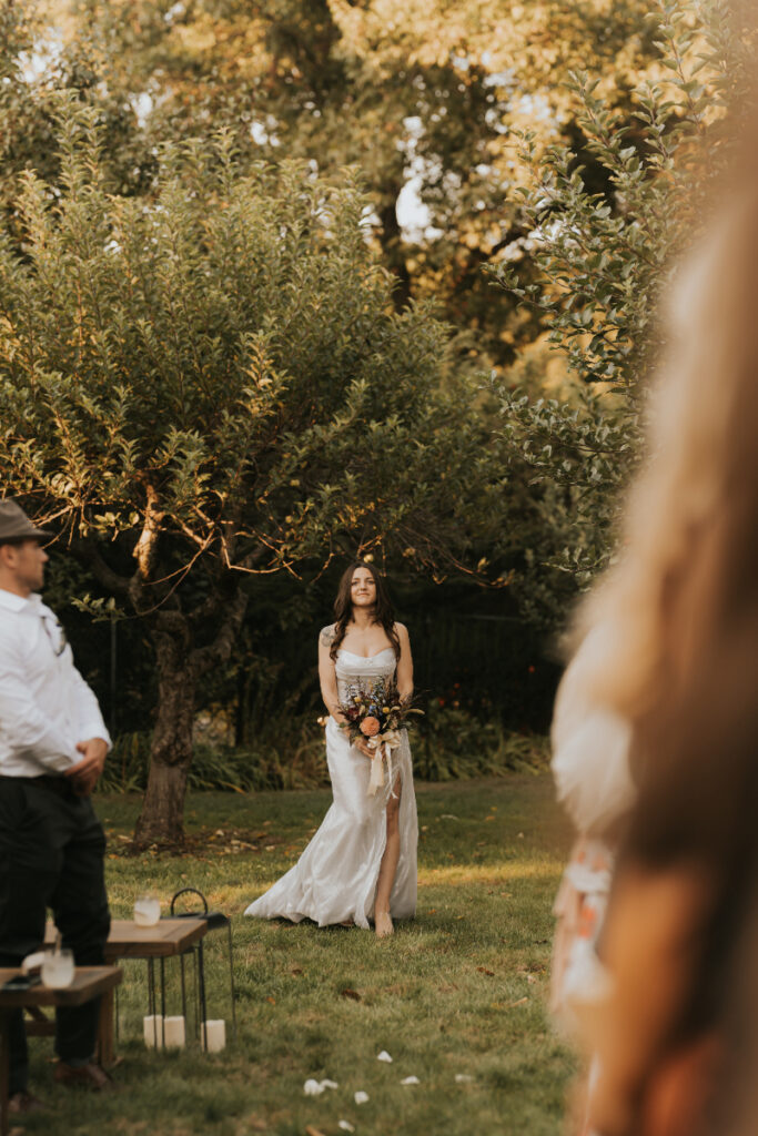 Bride walking across garden lawn during Italian countryside wedding ceremony.