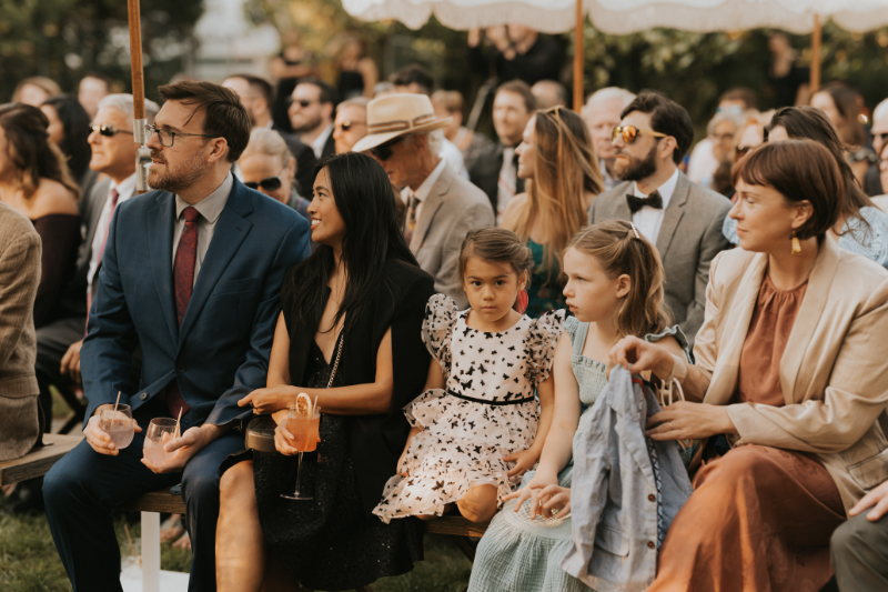 Guests seated with children during Italian countryside wedding ceremony outdoors.
