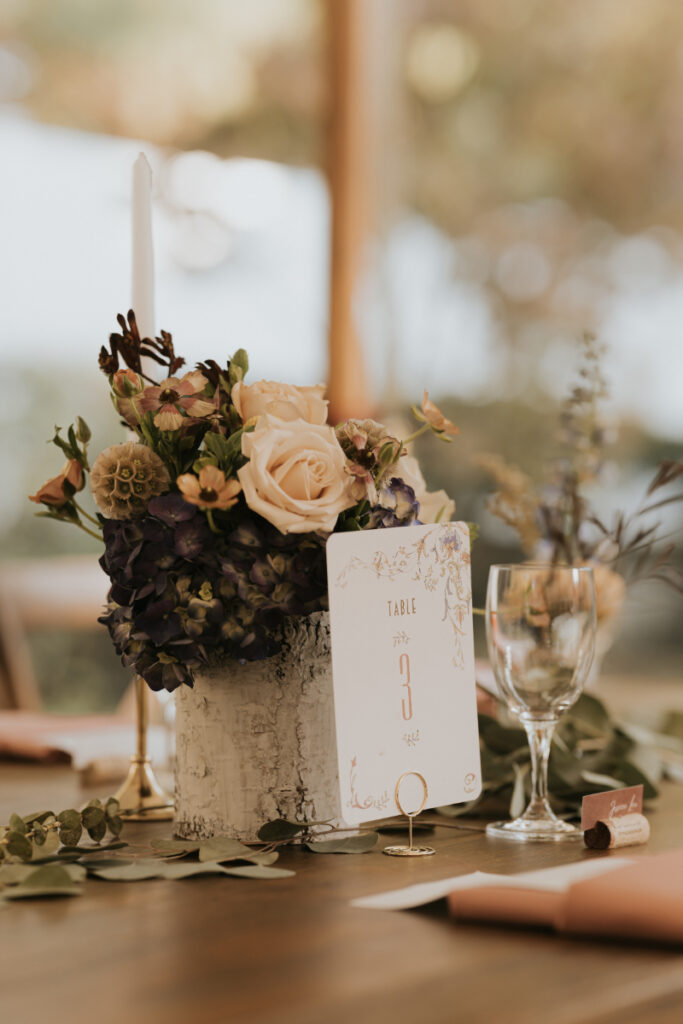 Floral centerpiece and table number at Italian countryside wedding reception.