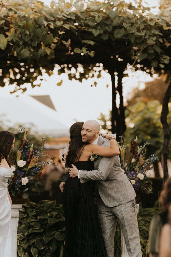 Groom hugging guest during Italian countryside wedding at family estate.
