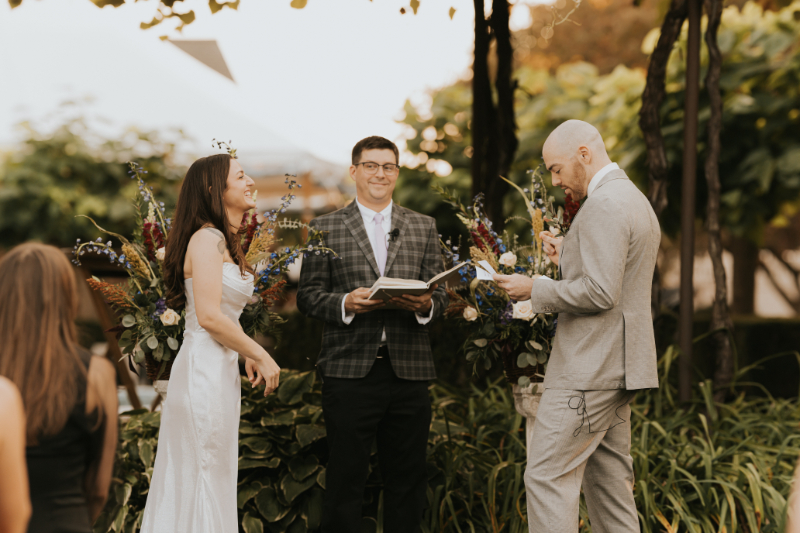 Officiant speaking during Italian countryside wedding under grape vine canopy