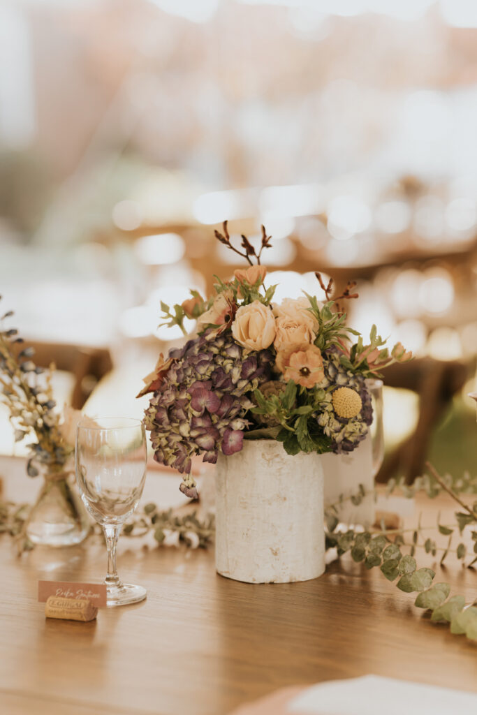 Moody floral arrangement on table at countryside wedding dinner.