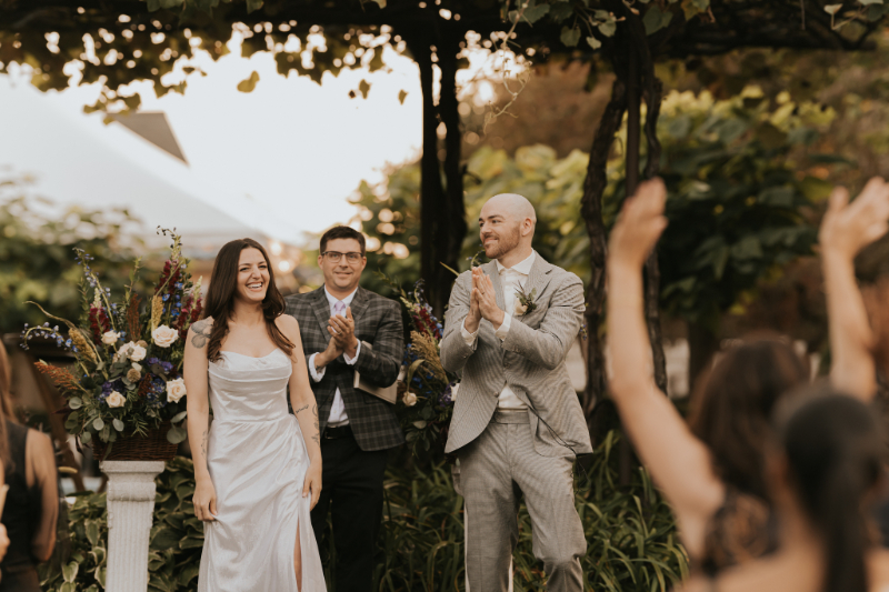 Groom clapping after vows at Italian countryside wedding ceremony.