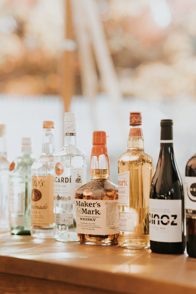 Bar setup with liquor bottles at Italian countryside wedding reception.
