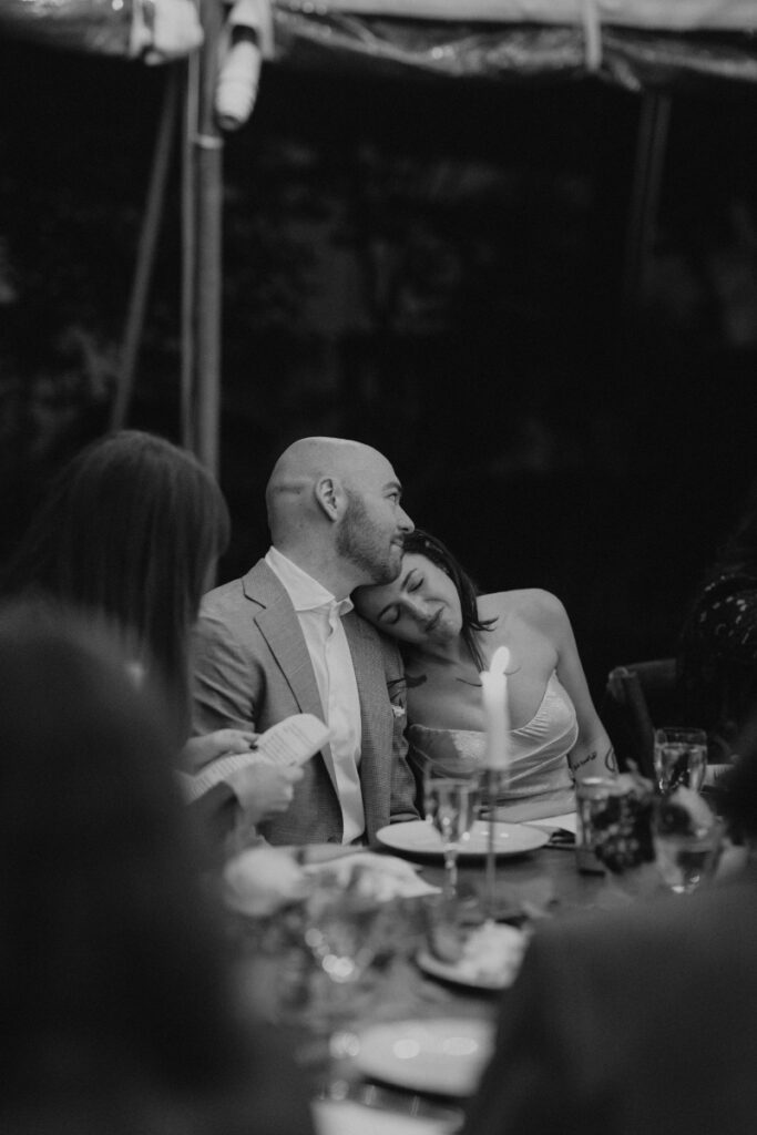 Couple leaning together at candlelit dinner during wedding reception.