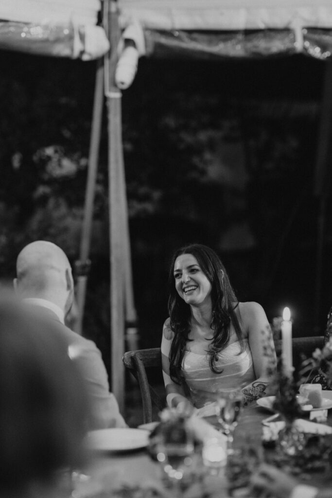Bride smiling at dinner during Italian countryside wedding reception.