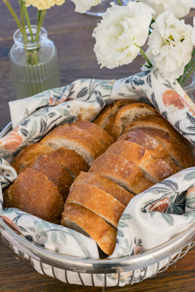 White tiered wedding cake decorated with lemon slices, greenery, and orange edible flowers.