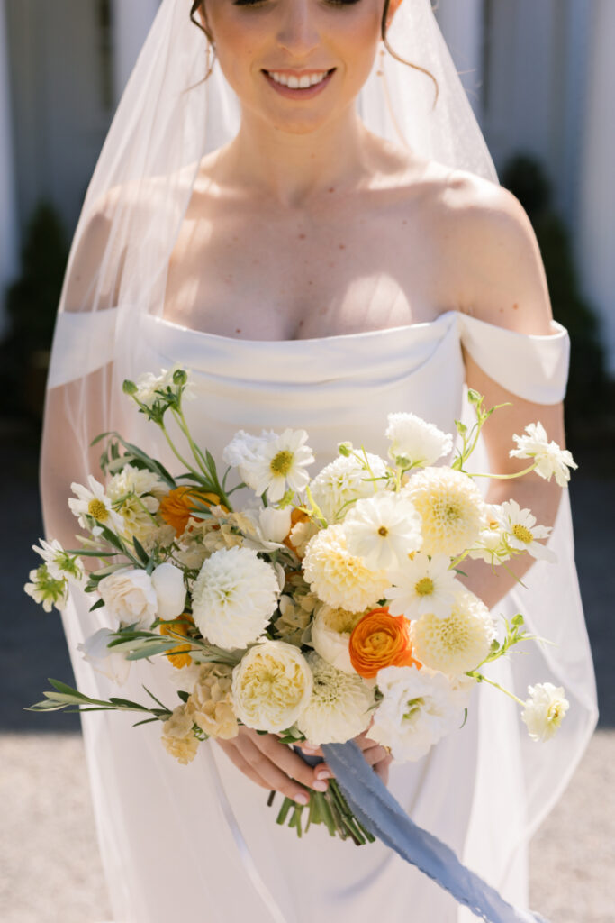 Bride holding white and yellow bouquet in off-the-shoulder gown at her wedding at Connemara House.